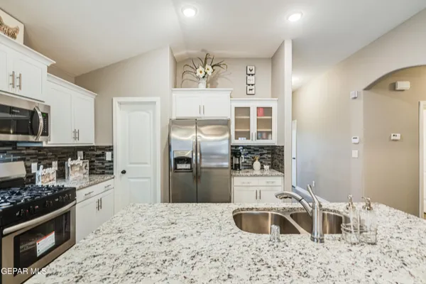 a kitchen with stainless steel appliances kitchen island granite countertop a refrigerator stove and sink
