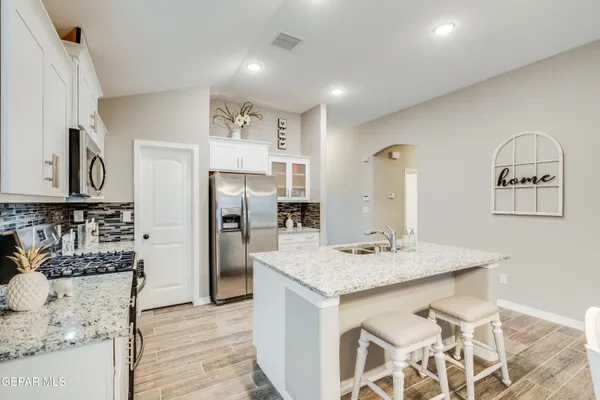 a kitchen with stainless steel appliances kitchen island granite countertop a refrigerator a stove and a sink