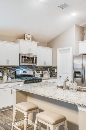 a kitchen with stainless steel appliances granite countertop a sink a stove a microwave a counter top space and cabinets