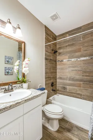 a bathroom with a granite countertop sink toilet a mirror and bathtub