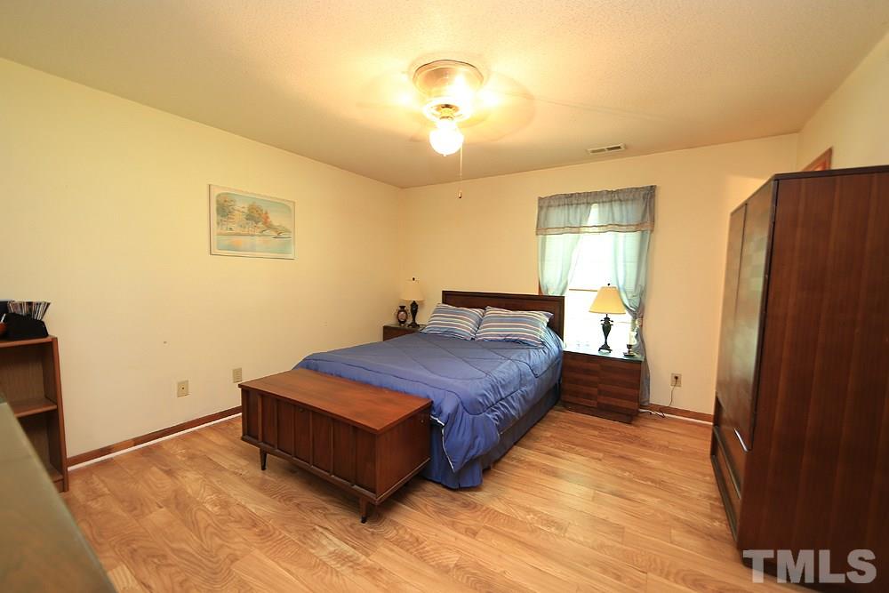 4509 Fox Road Raleigh, NC 27616 - Photo 8 of 13 a spacious bedroom with a bed and a chandelier