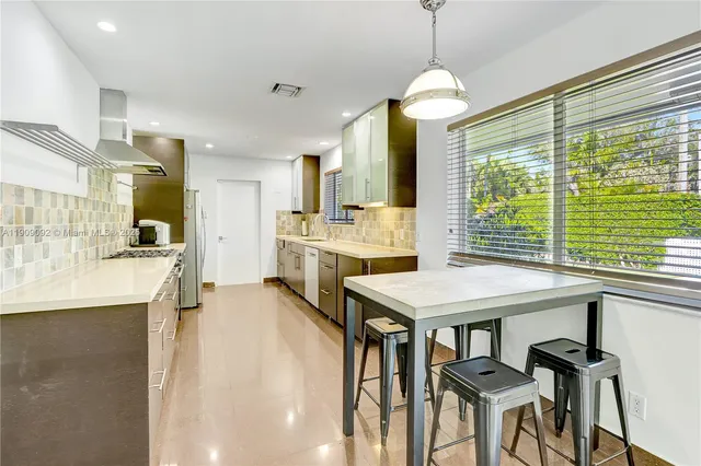 a room with a table chairs and a kitchen view