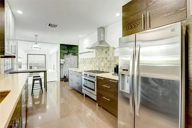 a kitchen with stainless steel appliances kitchen island granite countertop a refrigerator a stove and a cabinets with wooden floor