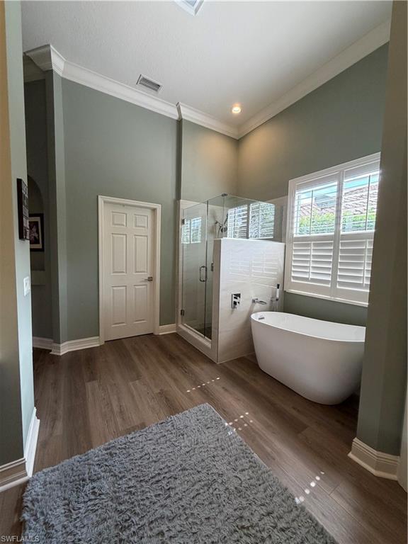2143 Grove Drive Naples, FL 34120 - Photo 17 of 37 Bathroom featuring a stall shower, a soaking tub, dark wood-style flooring, ornamental molding, and recessed lighting
