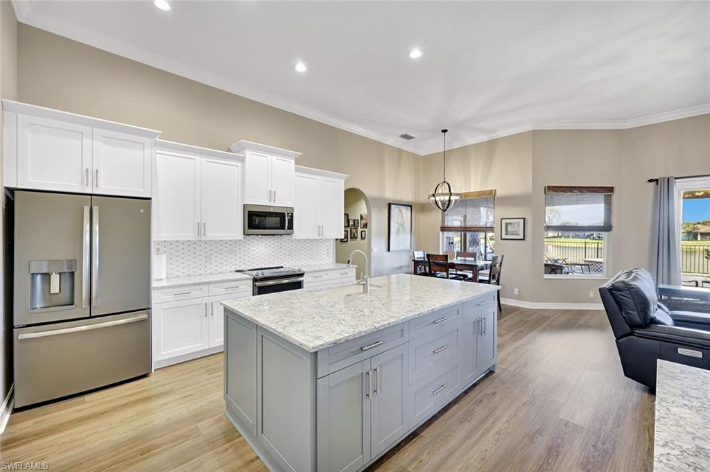 2143 Grove Drive Naples, FL 34120 - Photo 35 of 35 a large kitchen with a center island wooden floor stainless steel appliances and windows