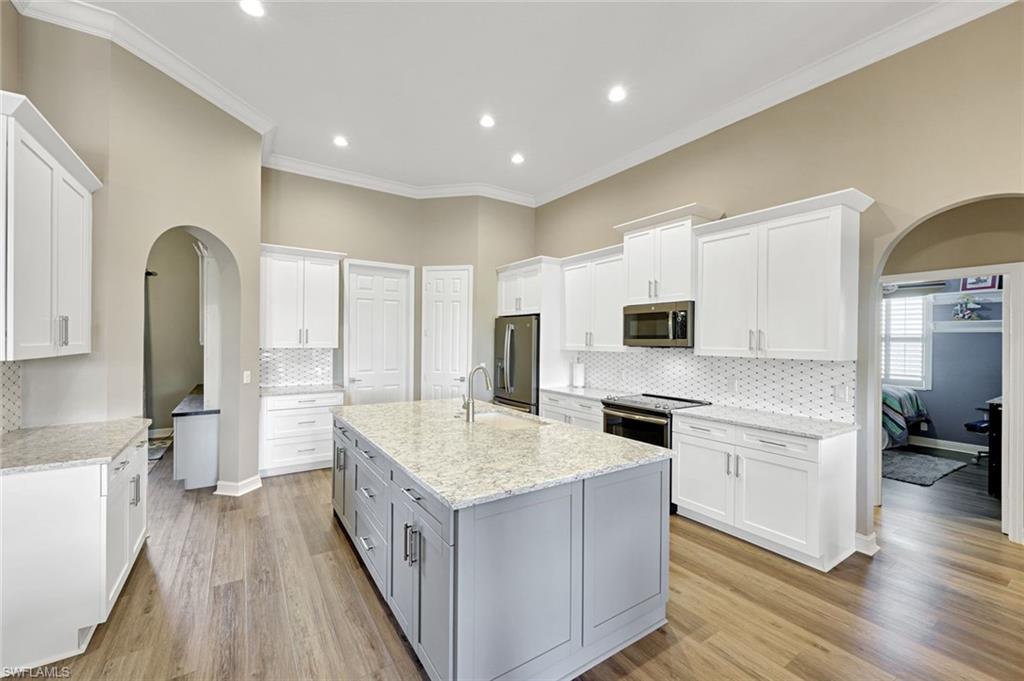 2143 Grove Drive Naples, FL 34120 - Photo 9 of 35 a large kitchen with stainless steel appliances granite countertop a lot of cabinets and wooden floor