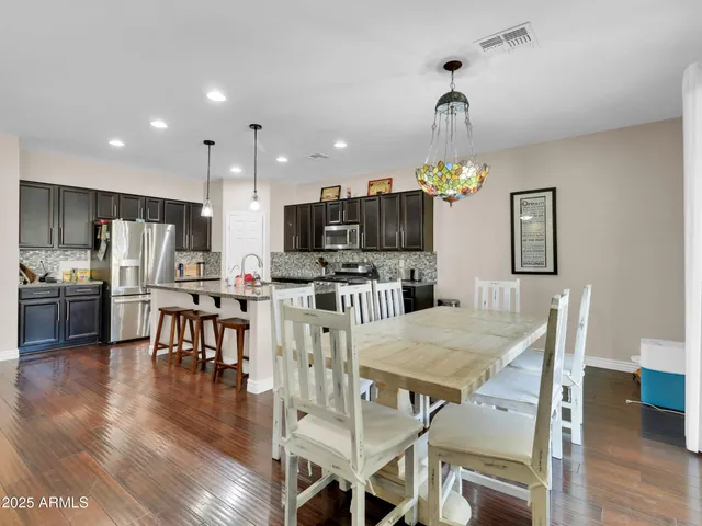 a kitchen with stainless steel appliances granite countertop a dining table chairs stove refrigerator and microwave