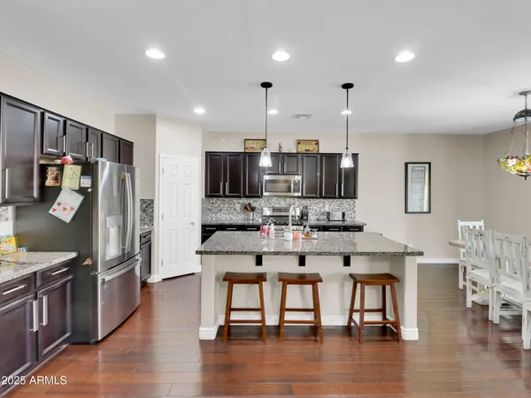 a kitchen with stainless steel appliances kitchen island granite countertop a refrigerator a stove a sink a dining table and chairs