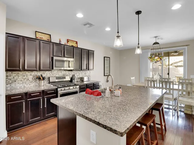 a kitchen with stainless steel appliances granite countertop a kitchen island a stove and a sink