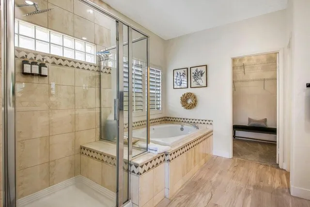 a bathroom with a tub a mirror and shower