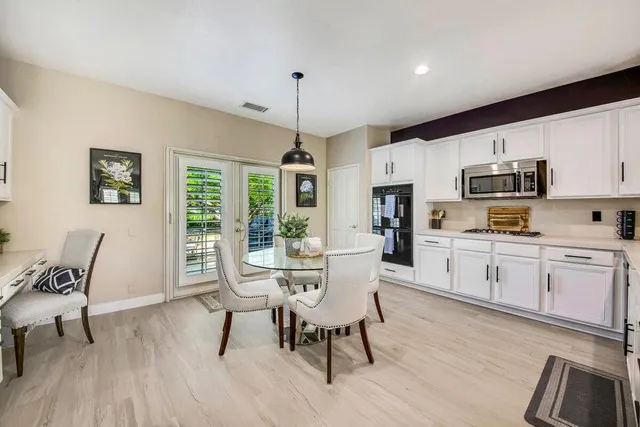 a kitchen with white cabinets and wooden floor