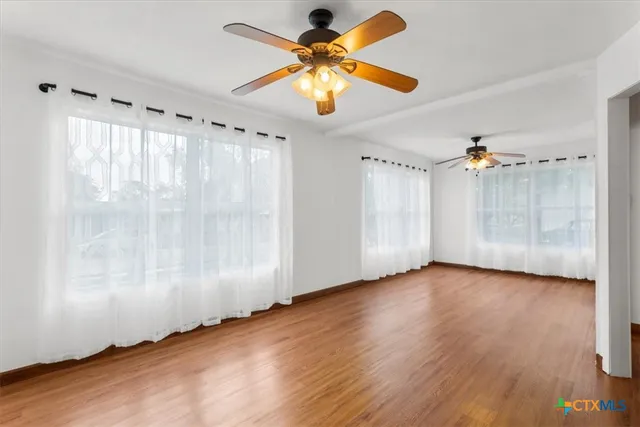 a view of an empty room with window and wooden floor