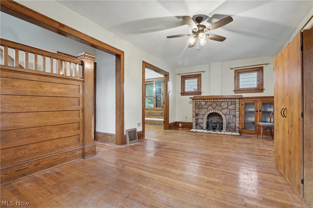 456 Delmar Avenue Akron, OH 44310 - Photo 5 of 27 Living area featuring wood-finish flooring, a stone fireplace, wood trim, and a ceiling fan