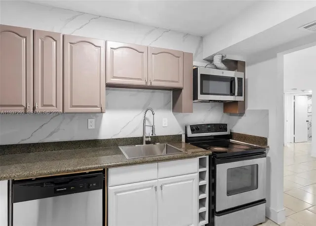 a kitchen with granite countertop white cabinets and stainless steel appliances