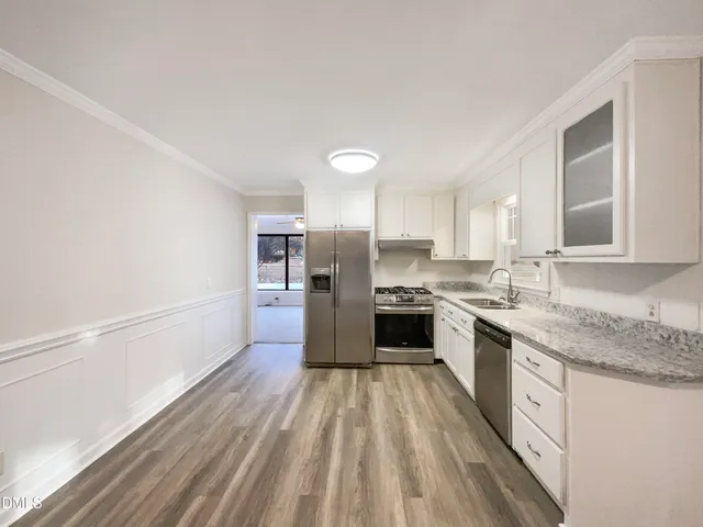 a large kitchen with a center island wooden floor and stainless steel appliances