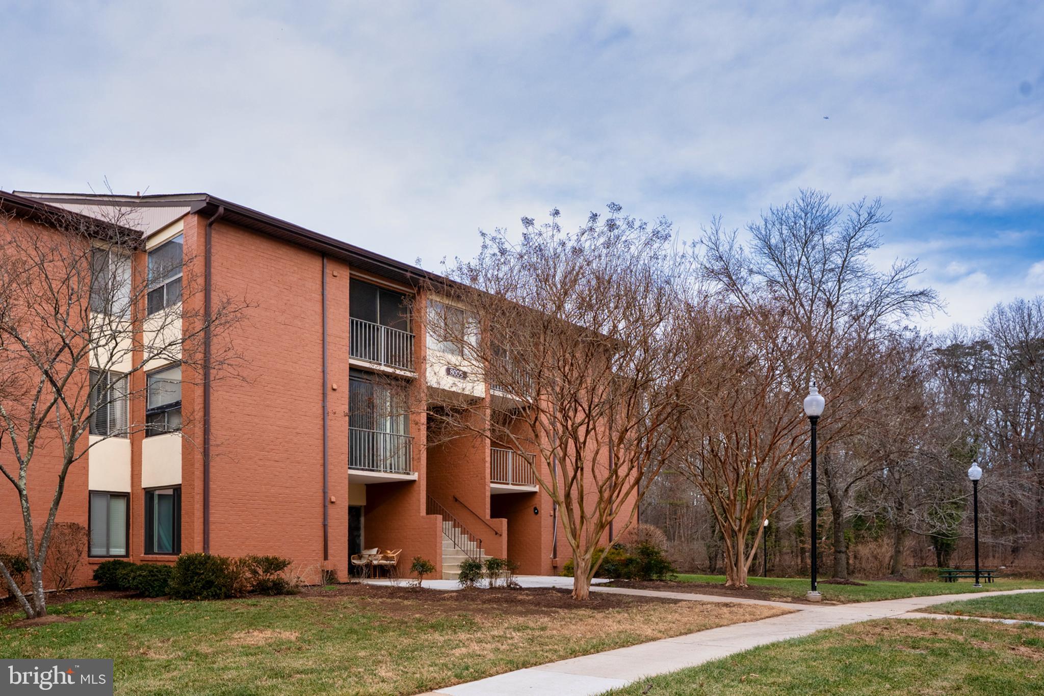 8005 Mandan Road, Unit 302 Greenbelt, MD 20770 - Photo 1 of 22 a front view of house with yard and trees around