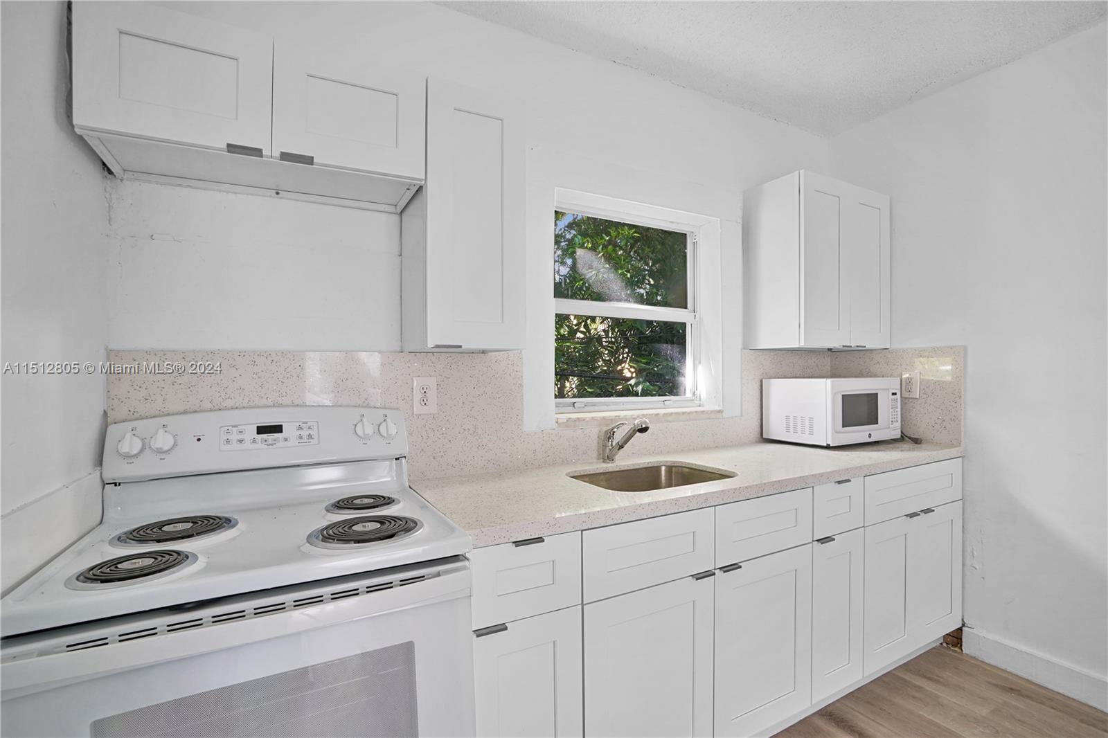 1924 Southwest 9th Street Miami, FL 33135 - Photo 14 of 23 a kitchen with stainless steel appliances granite countertop a sink stove and white cabinets