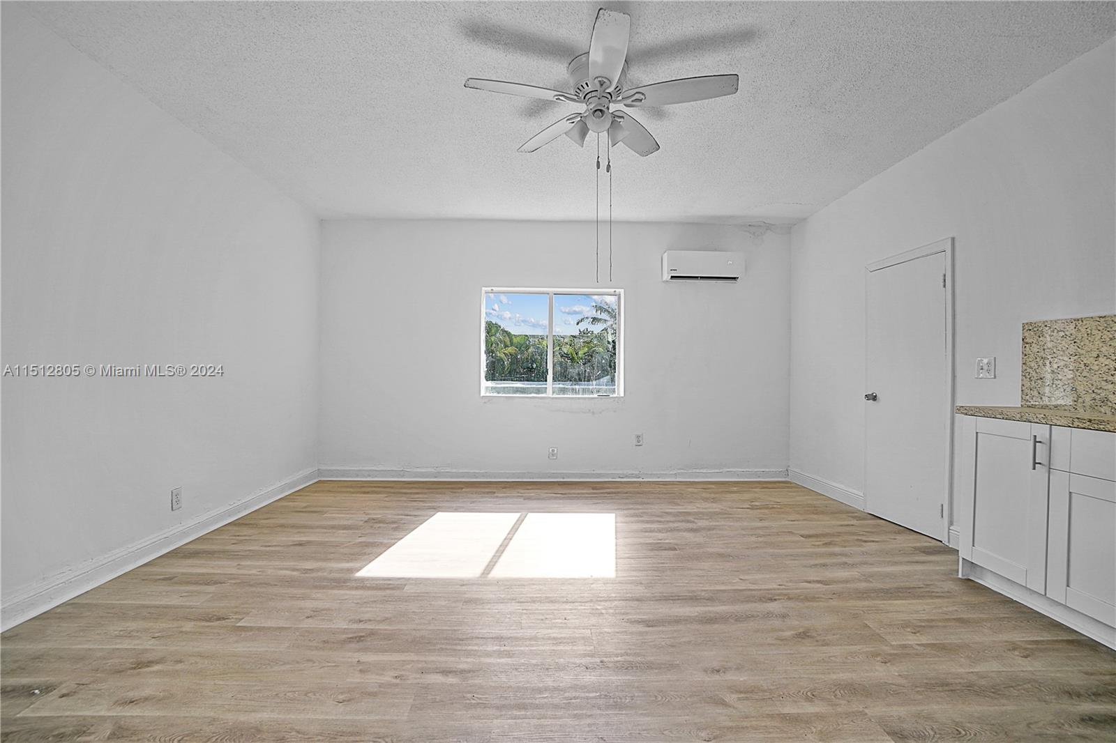 1924 Southwest 9th Street Miami, FL 33135 - Photo 10 of 23 an empty room with wooden floor chandelier fan and windows