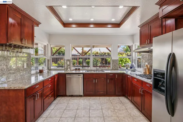 a large kitchen with stainless steel appliances granite countertop a sink and wooden cabinets