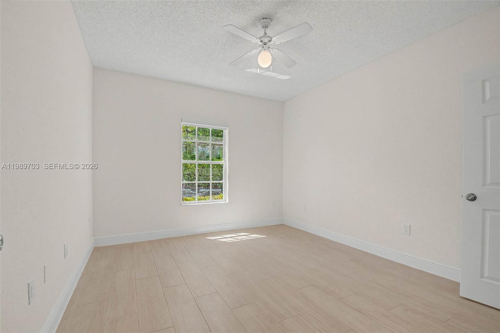 7000 Southwest 80th Street, Unit 103 Miami, FL 33143 - Photo 6 of 16 an empty room with a window and a ceiling fan