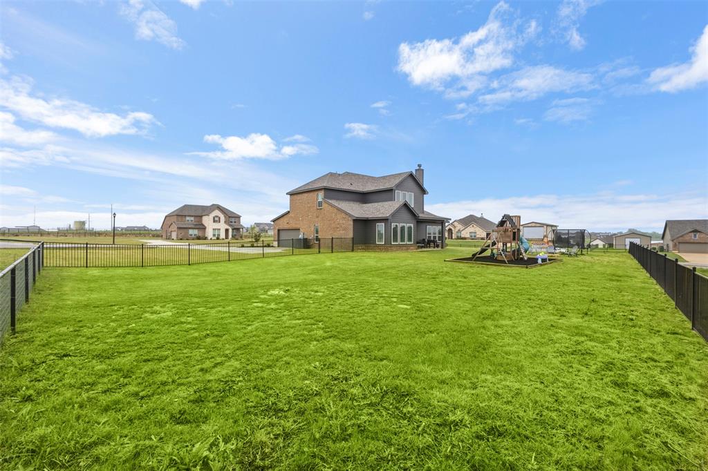 107 Yampa Court Rhome, TX 76078 - Photo 27 of 30 Expansive fenced backyard featuring a large green lawn, brown brick and gray siding exterior, and a playset