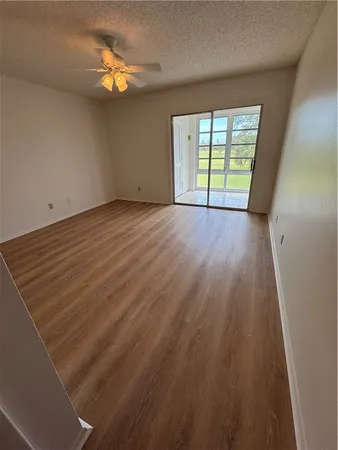 a view of an empty room with a window and wooden floor