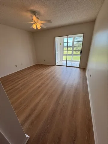 a view of an empty room with a window and wooden floor