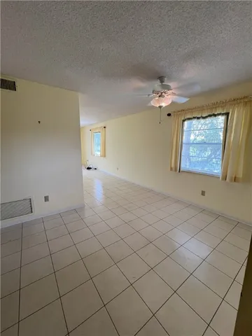 a view of a livingroom with a chandelier fan and windows