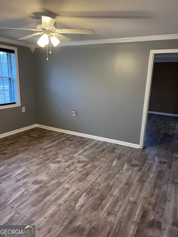 a view of an empty room with window and wooden floor