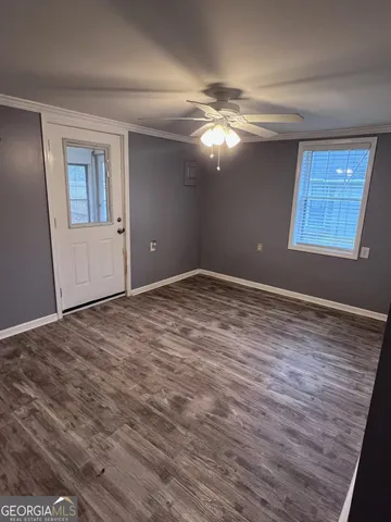 a view of an empty room with window and wooden floor