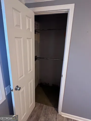 a view of a hallway with wooden floor and a bathroom