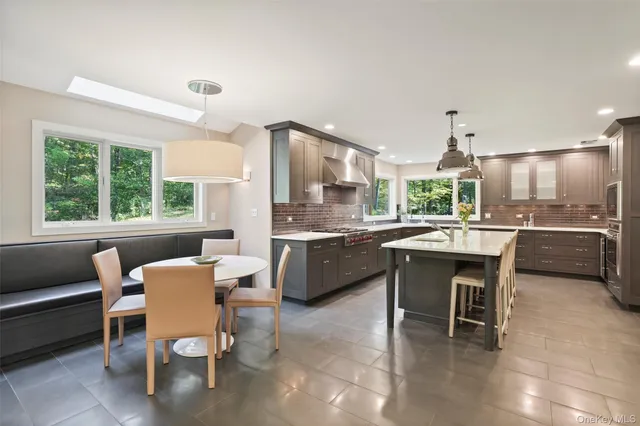 a dining hall with stainless steel appliances kitchen island a table and chairs in it