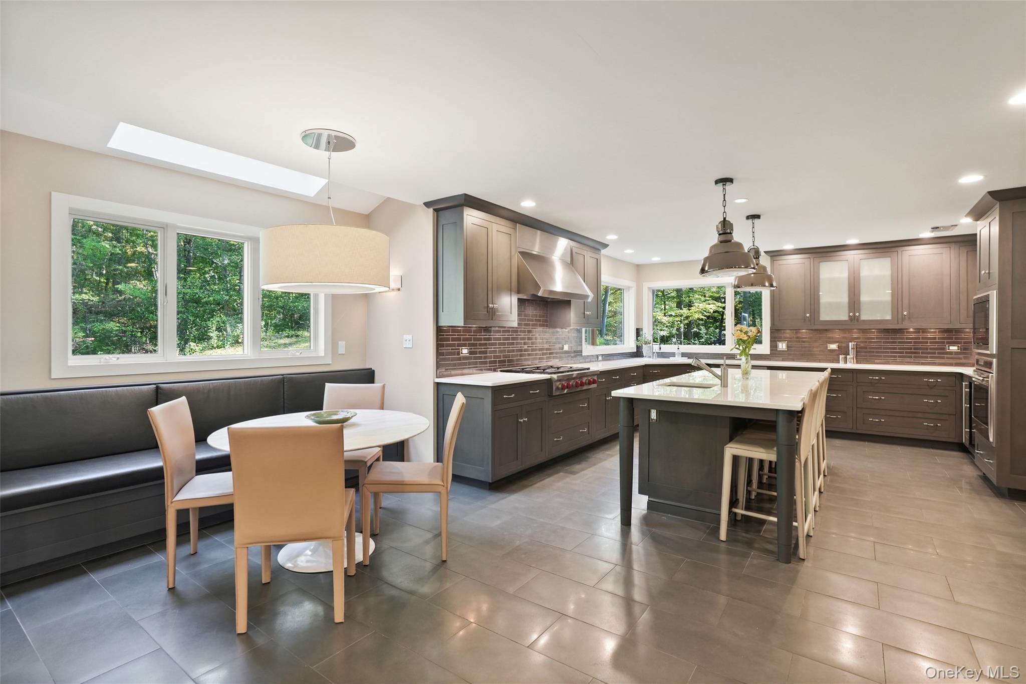a dining hall with stainless steel appliances kitchen island a table and chairs in it