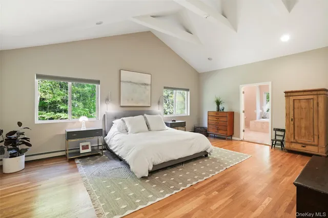 a spacious bedroom with a bed a dresser and a large window