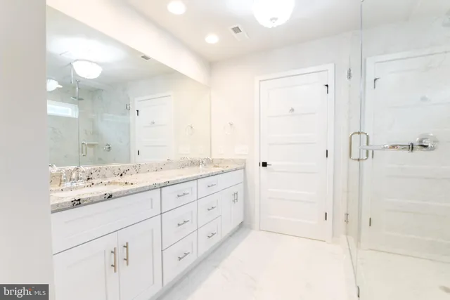 a bathroom with a granite countertop sink mirror and shower