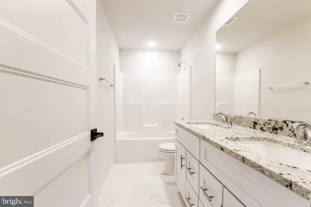 a bathroom with a granite countertop sink a toilet and shower