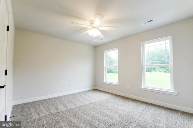 an empty room with a chandelier fan and closet area