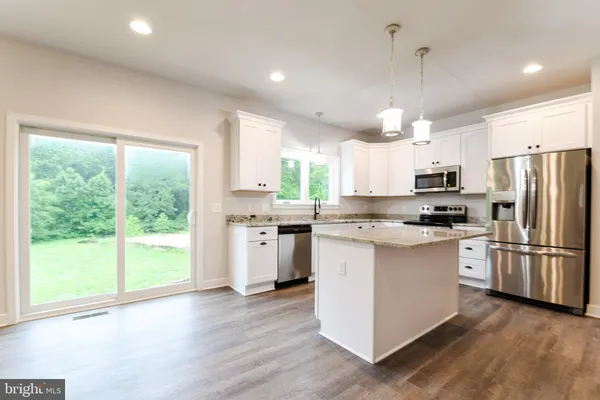 a kitchen with stainless steel appliances granite countertop a refrigerator a stove a sink dishwasher a microwave oven with white cabinets and wooden floor