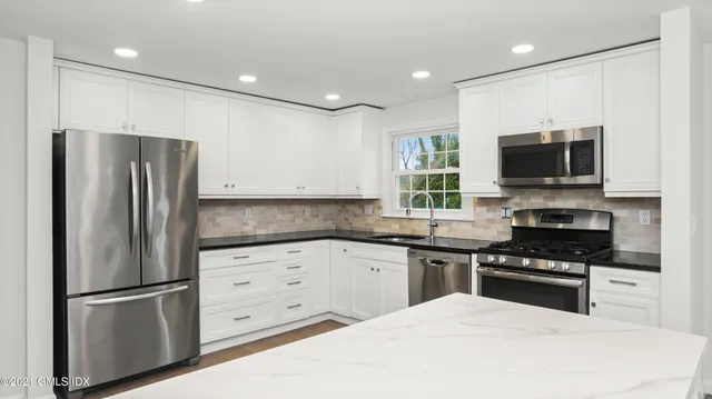 a kitchen with granite countertop a refrigerator stove and microwave