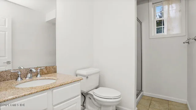 a bathroom with a granite countertop toilet and a sink