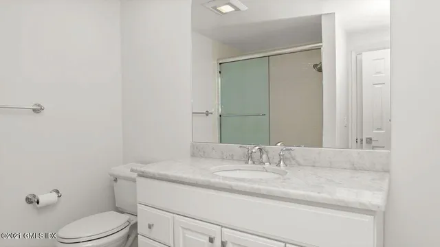 a bathroom with a granite countertop sink toilet and mirror