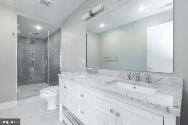 a bathroom with a granite countertop sink a toilet a shower and a mirror