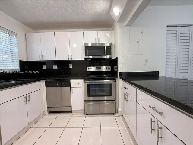 a kitchen with granite countertop white cabinets and black appliances