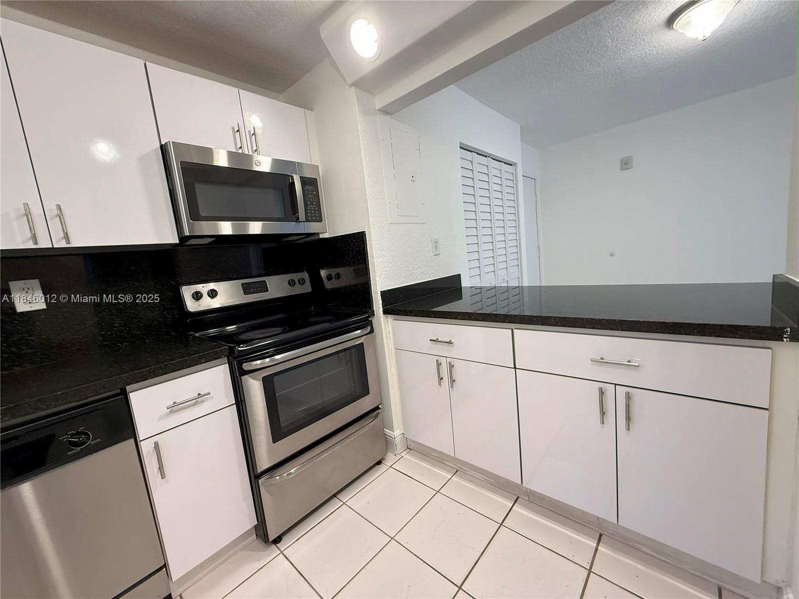 816 Northwest 87th Avenue, Unit 107 Miami, FL 33172 - Photo 6 of 20 a kitchen with granite countertop white cabinets and black appliances