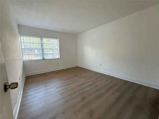 a view of an empty room with closet and a window