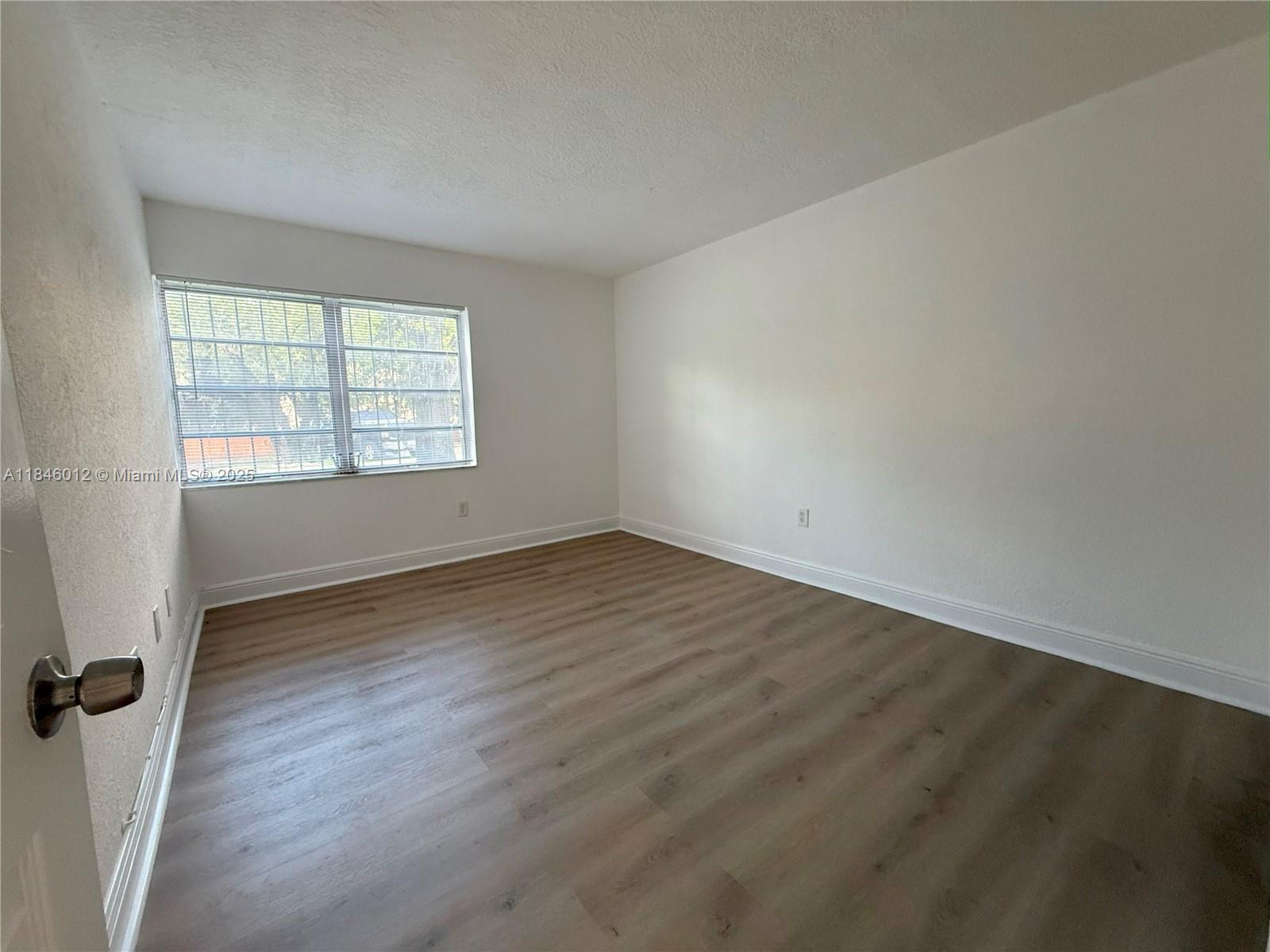 816 Northwest 87th Avenue, Unit 107 Miami, FL 33172 - Photo 7 of 20 an empty room with wooden floor and windows