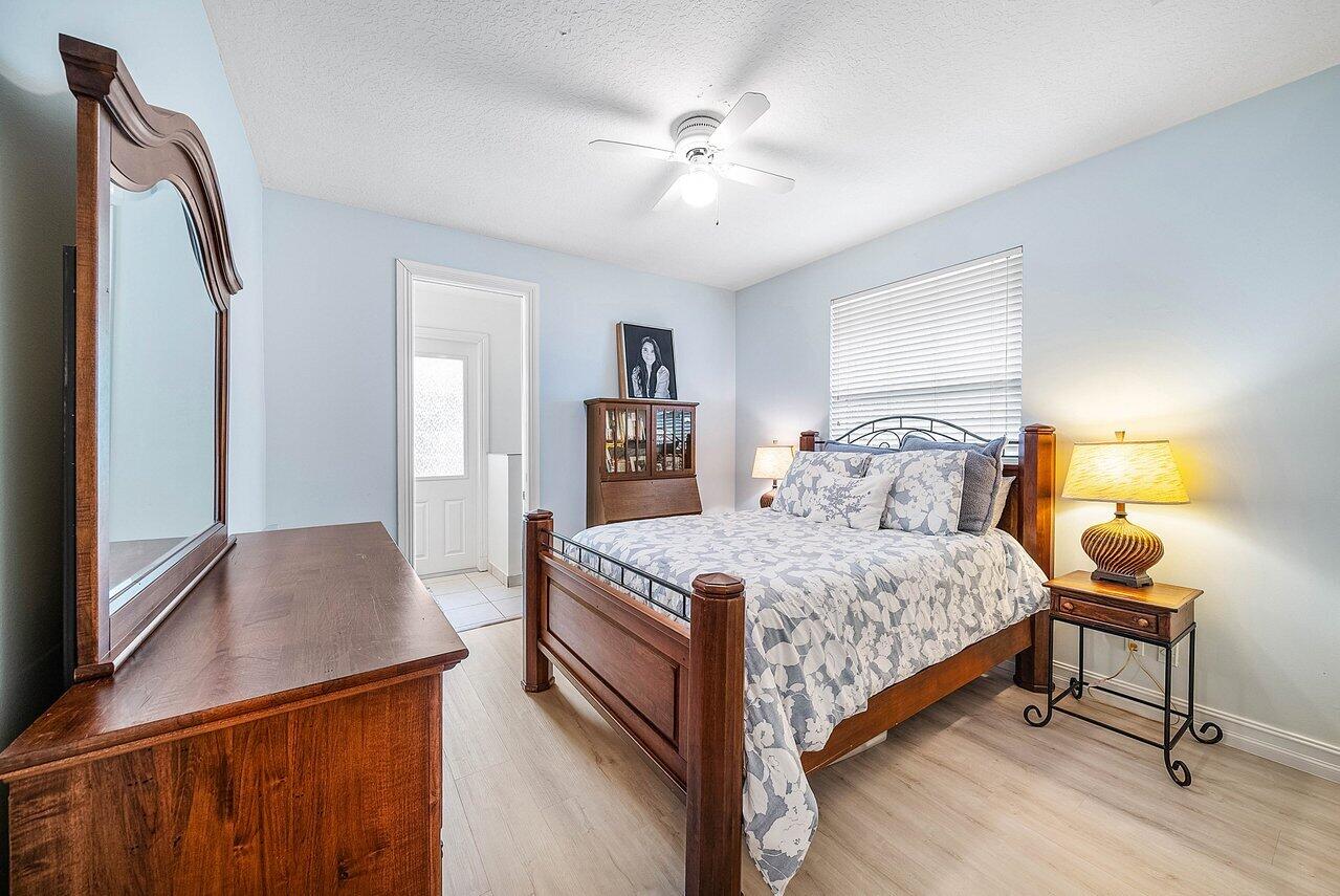 2560 Whispering Oaks Lane Delray Beach, FL 33445 - Photo 29 of 41 a bedroom with a bed and a chandelier