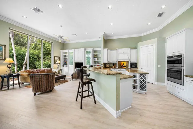 an open kitchen with kitchen island granite countertop a large counter top stainless steel appliances and windows