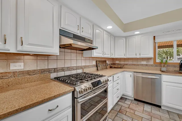 a kitchen with white cabinets and appliances