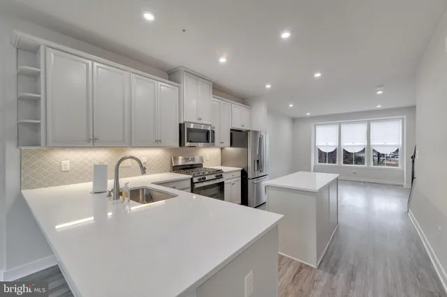 a view of a kitchen with kitchen island a sink stainless steel appliances and cabinets